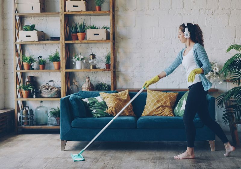 Cleaner mopping a timber floor in a living room