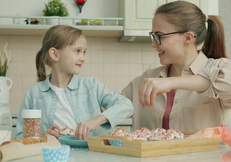 Carer and a young girl baking together in a kitchen